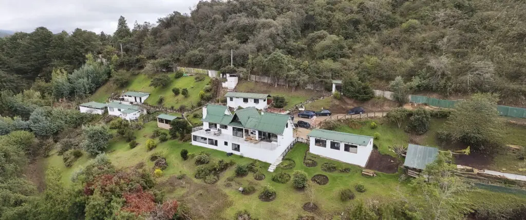 vista panorámica con dron de la finca El Silencio del Sisga, casas blancas de campo con techo verde en la naturaleza