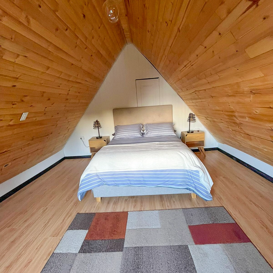 Cama doble con edredón de líneas azules, mesas de noche de madera clara y lámparas de mesa rústicas