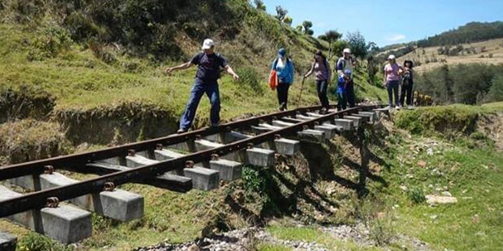 Personas caminando por la carrilera del tren en medio de la naturaleza - caminatas ecológicas